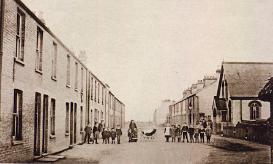 Family group standing in Alpha Terrace, looking east with the Free Church on the right, postcard c. 1908. Photograph: Cambridgeshire Collection.