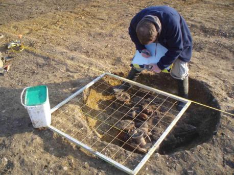 Recording the finds in situ in the cremation pit. Source: Oxford Archaeology East, 9 February 2011.