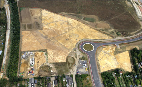 Aerial view of the archaeological excavation on Clay Farm, looking east from Shelford Road. The old railway line is to the left (being converted into the Busway), with the newly built Addenbrooke’s Road and roundabout to the right. Evidence of Middle Bronze Age ditches can be seen in the areas cleared of topsoil. The Abode development has now been built on these cleared areas, with the Paragon development built on land to the upper right. Oxford Archaeology East, July-August 2010.