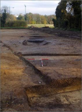 Excavating the ditch in the northern part of Clay Farm, Settlement 1. The tree belt is to the right. This land is now covered by Green Lane, Halo development, with Lime Avenue going from left to right in the area beyond the cleared topsoil and Trumpington Community College in the area upper right in sunlight. Oxford Archaeology East, February 2011.