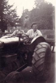 Ron Goodliffe on the tractor, with Brian sitting beside his father and Michael standing on the trailer, 1956