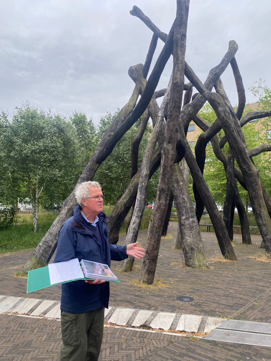 Andrew Roberts talking to the participants on the Local History Group walk from Hobson Square to Long Road, beside the Bronze House artwork in Hobson Square. Photo: Tirza Bleehen, 5 June 2025.