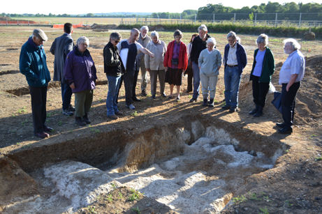 Participants looking at one of the Late Saxon/Early Medieval sunken structures with the river valley in the background, Trumpington Meadows archaeological site. Photo: Andrew Roberts, 24 May 2011.