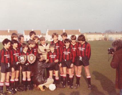 Trumpington Tornadoes: Daren Haylock holding the 2 shields and his father, Neville Haylock, behind him. Manager - Tom Davison. Possibly u13 team c1982. [Source: supplied by Mrs V. Pearson]