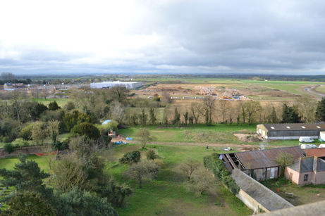 Looking from Trumpington church tower south over the outbuildings of Anstey Hall Farm, across Trumpington Meadows, with the field examined during the archaeology excavation in the foreground, the first homes to the left, the John Lewis building, the area for the primary school and the higher part of the park, towards the motorway and Hauxton. Photo: Andrew Roberts, 7 April 2012.