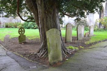 The Nightingale headstone with circular Celtic cross and Dobson headstone, under the yew tree near the junction of the path from the porch and the path to the west of the tower (entry 4 and 5). Photo: Andrew Roberts, 27 October 2013.